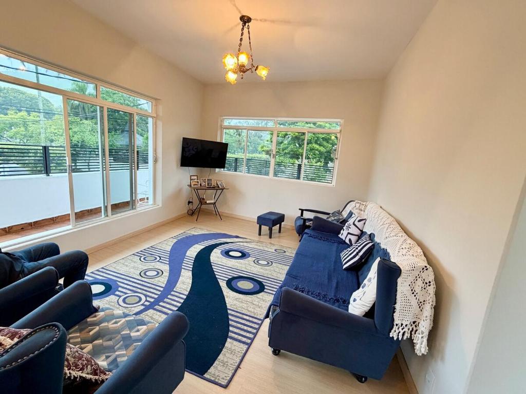 a living room with a blue couch and a rug at Nogueira Home in Passa Quatro