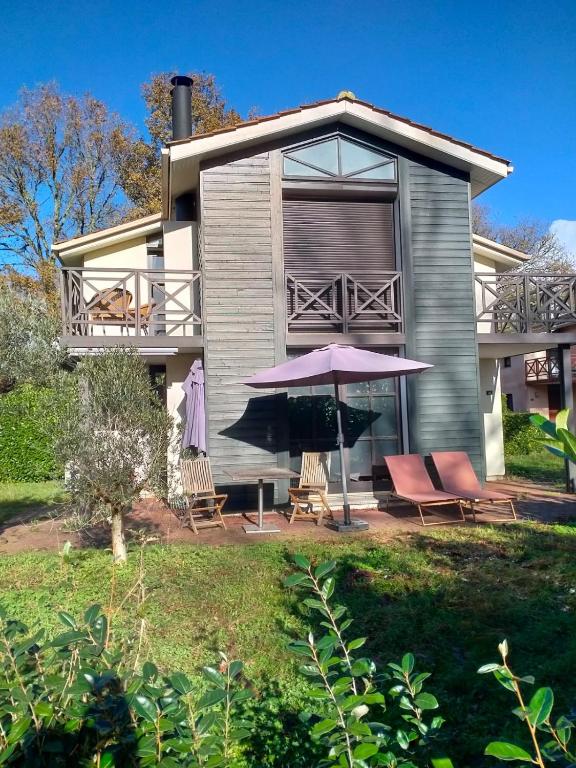 a house with chairs and an umbrella in front of it at Villa de l Eyre in Salles