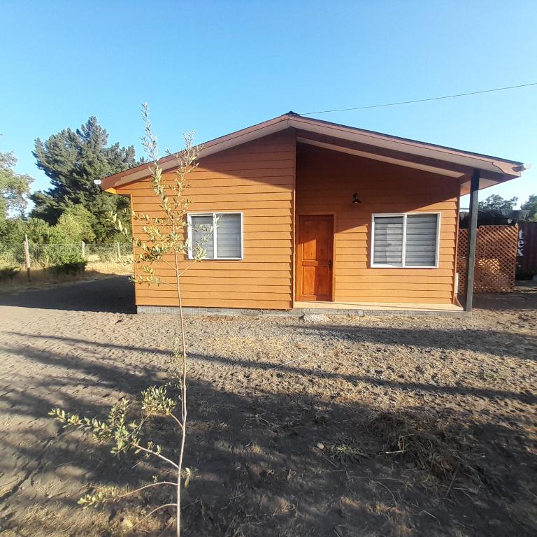 a small yellow house on a dirt road at Quillon cabañas in Quillón