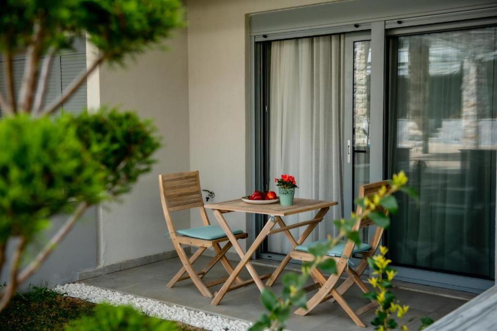 a table and two chairs on a patio with a window at Studio Apartments Itaka in Nikiti