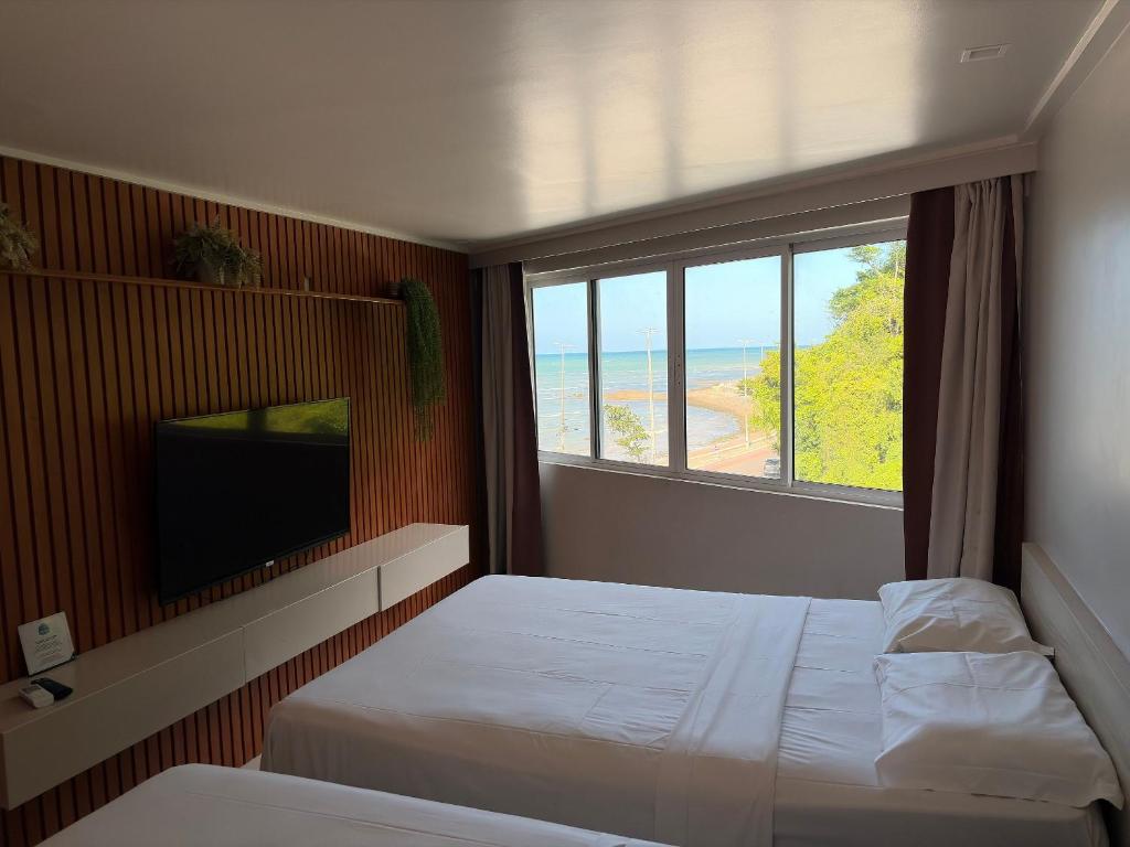 a bedroom with a bed and a window with a view of the beach at Flat em Cabo Branco - Blue Sunset in João Pessoa