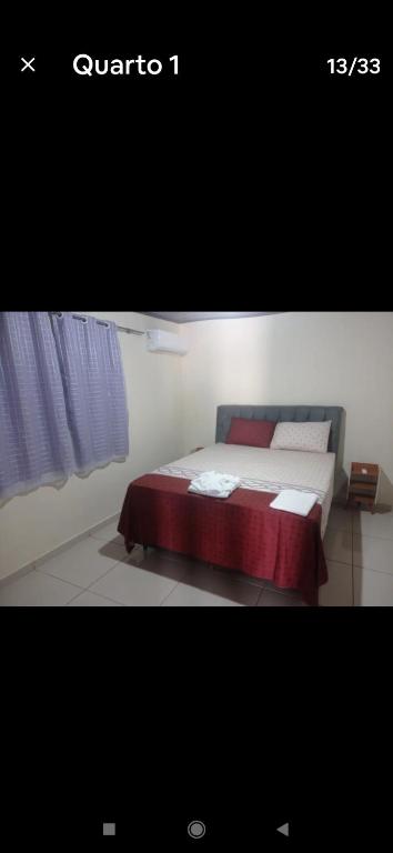 a bedroom with a bed with a red blanket at Recanto do Garças in Aragarças