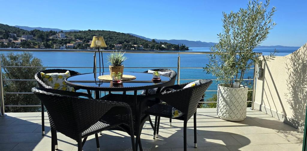 a table and chairs on a balcony with a view of the water at Villa Ružmarin in Lovište