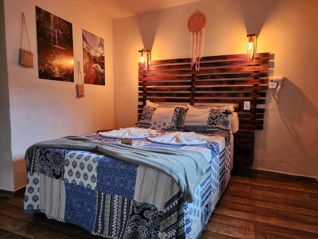 a bedroom with a bed with a wooden headboard at Suítes Aconchego - Pousada Rústica & Café da Manhã Especial in Lençóis