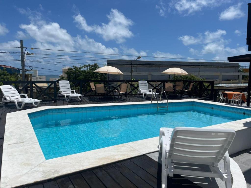 a swimming pool with two chairs and a table at Breeze Hotel in Natal