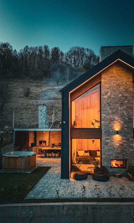 a brick house with a large window and a fireplace at Aftăr Hills in Poiana Mărului