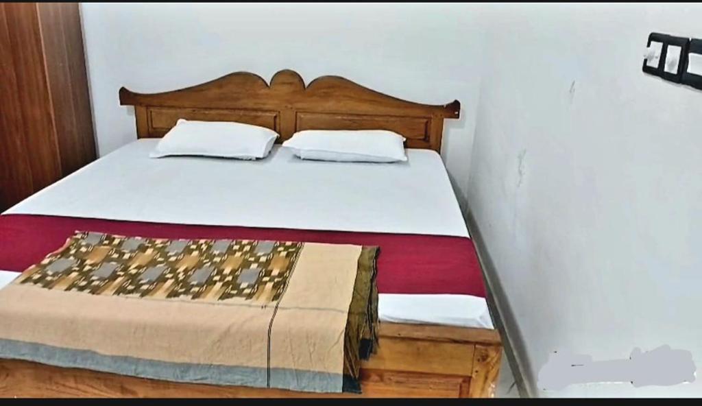 a bed with a wooden headboard in a bedroom at Kanmani Guest House in Kondavil