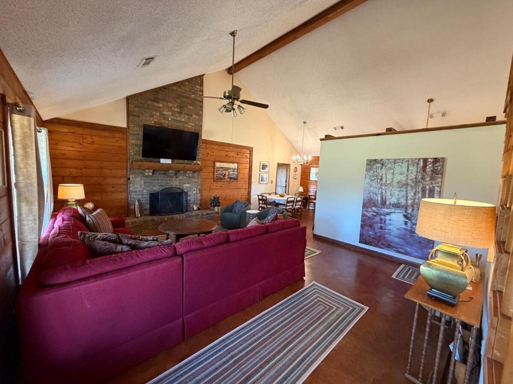 a living room with a purple couch and a fireplace at The Piney Woods Cabin in Nacogdoches