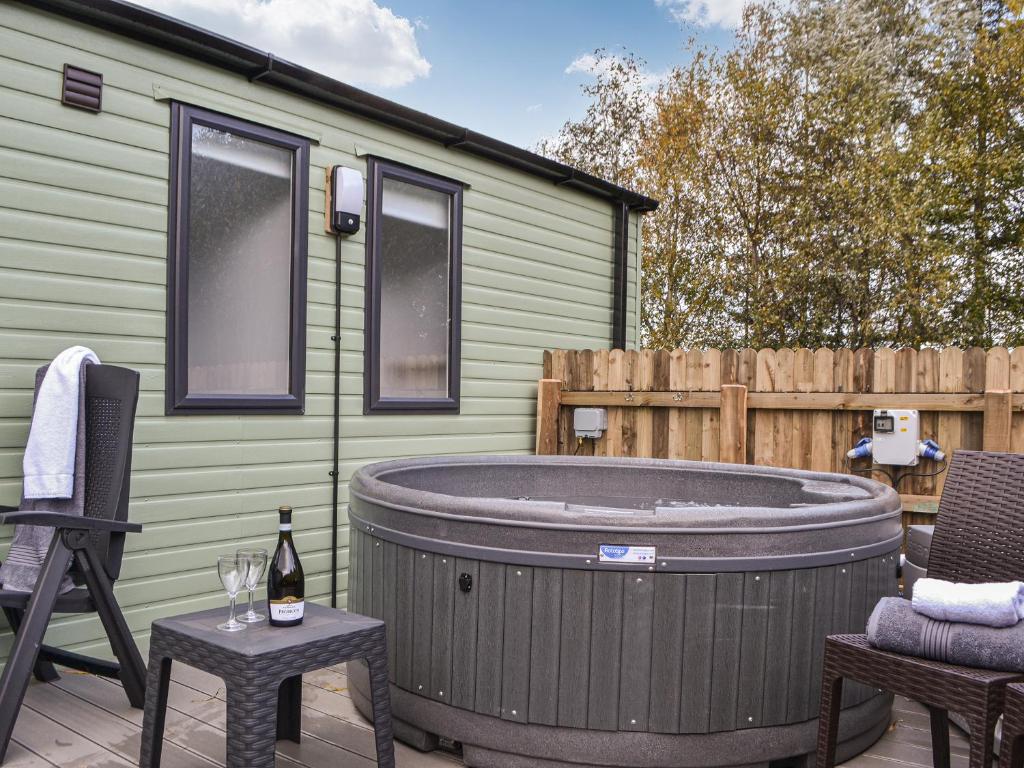 a hot tub on a patio next to a green trailer at Willow - Uk36374 in Westward
