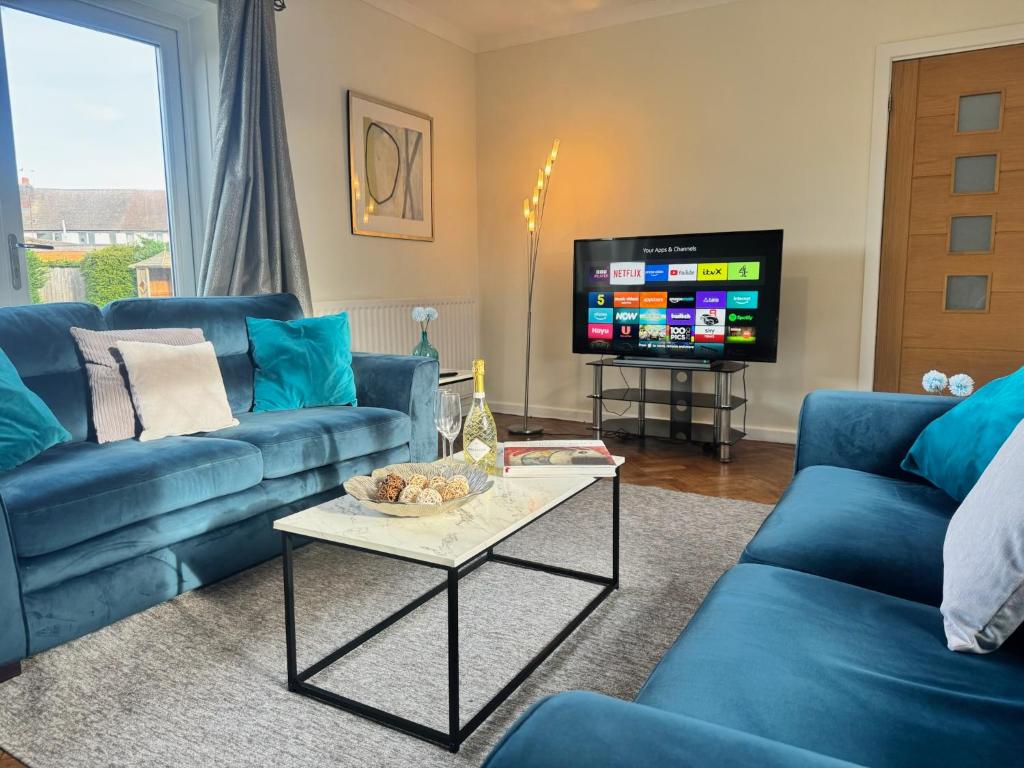 a living room with blue couches and a tv at Very Spacious 4 Bedroom house with large garden in Leamington Spa