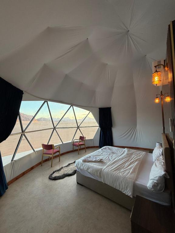 a bedroom with a bed and a view of the desert at Elite Rum Camp in Disah