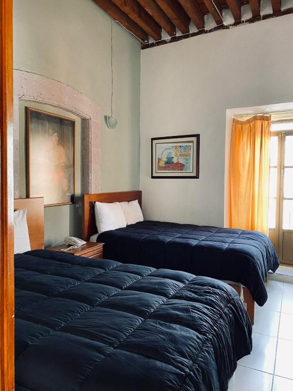 a bedroom with two beds and a window at Hotel Santo Domingo in Zacatecas