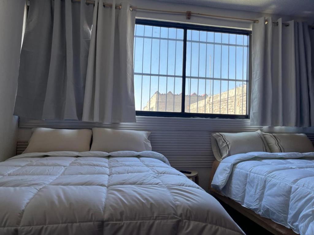 a bedroom with two beds and a large window at Alojamiento Artemisa in Mexico City
