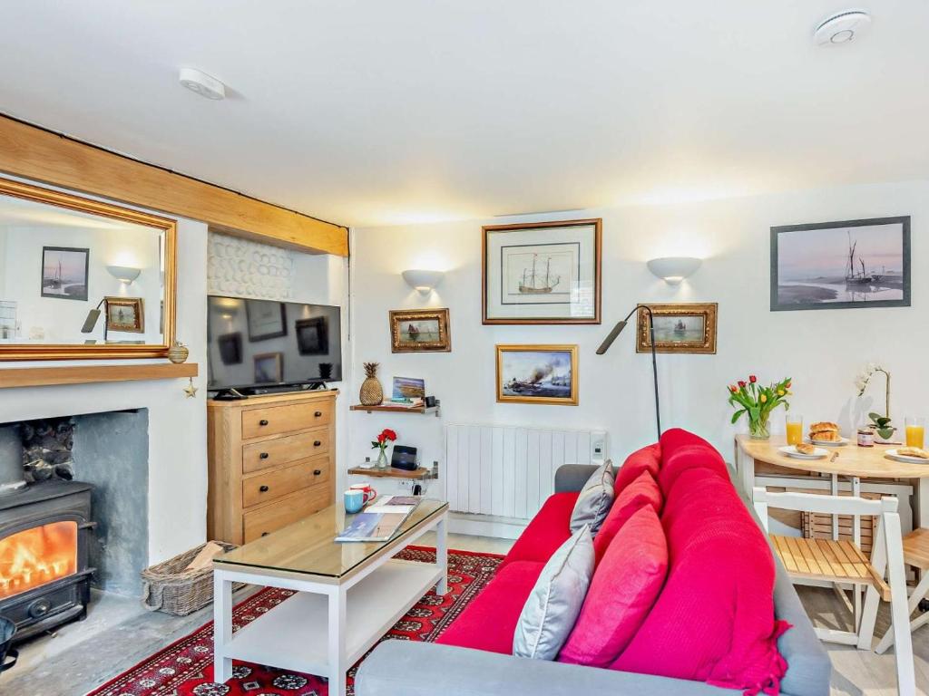 a living room with a red couch and a fireplace at 2 Bed in Holt oc-78478 in Blakeney