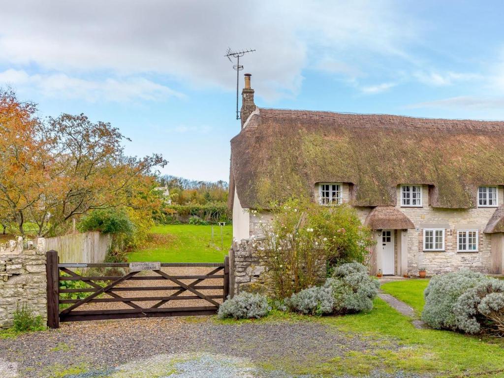 an old stone house with a gate and a thatch roof at 3 Bed in Dorchester oc-dc089 in Whitcombe