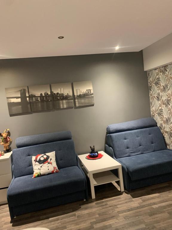 a living room with two blue couches and a table at Apartament Gospodarcza in Sosnowiec