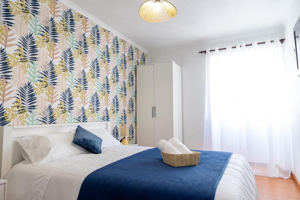 a bedroom with a bed with a blue blanket and a wallpaper at Central Square in Povoação