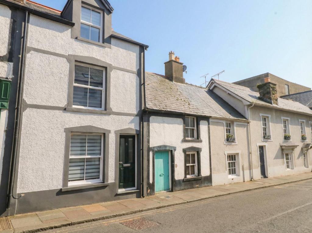 a white house with a blue door on a street at Chandlers Cottage in Conwy