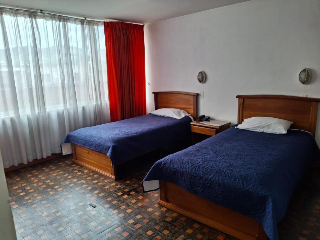 a hotel room with two beds and a window at Hotel Rio Mayo in Pasto