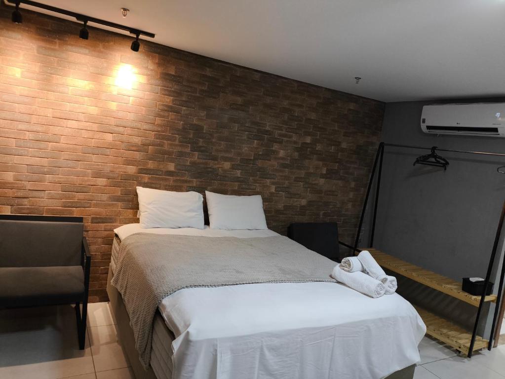 a bedroom with a bed and a brick wall at Flat Palmas Vivence Suítes in Palmas