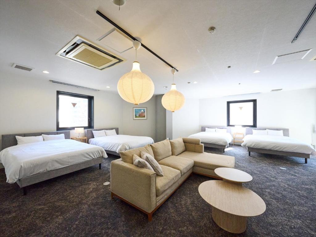 a large room with two beds and a couch and tables at Retrospect Stay Kannai in Yokohama