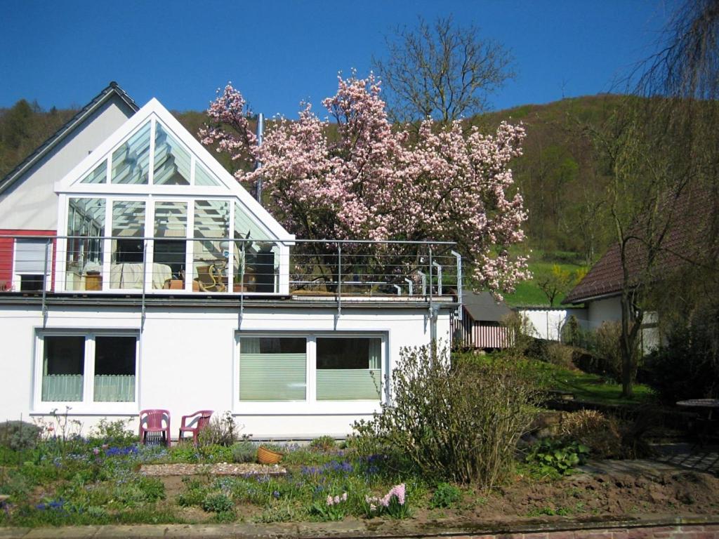 Una casa blanca con un árbol floreciente encima. en Apartment in L wensen with private terrace, en Bad Pyrmont
