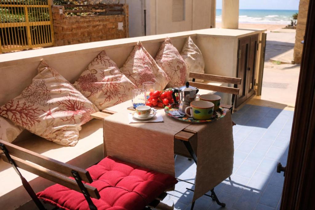 a table and chairs on a balcony with pillows at Lido Apartment in Donnalucata