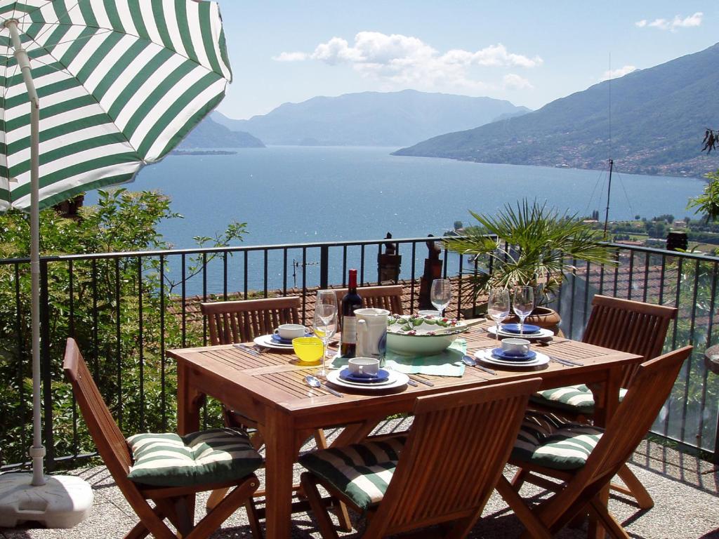 a wooden table with chairs and an umbrella on a balcony at Rosato in Gravedona