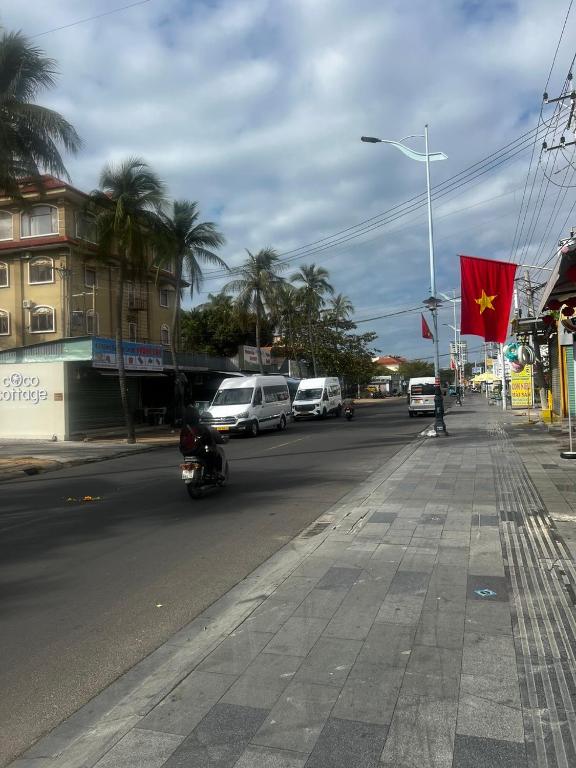 a street with cars and a red flag on a pole at Homsetay Đồng Phát in Ấp Thiện Phước