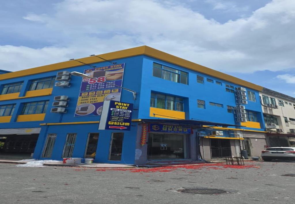 a blue and yellow building with a parking lot at Point Stay BDC Airport in Kuching