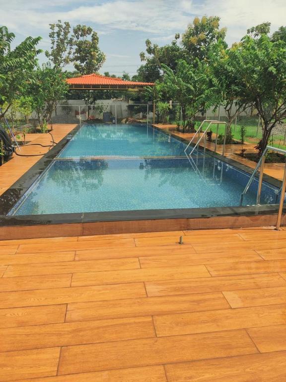 a large swimming pool with a wooden floor at Siva Rama garden resort 6 AC Bed rooms ,swimming pool ,BoX cricket ,Born fair,BBQ, kichan&all, near beach road bheemilli vishakapatnam in Visakhapatnam