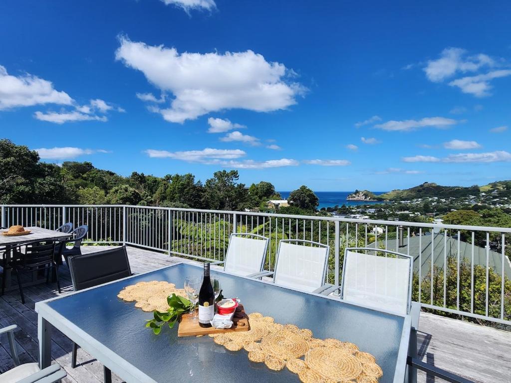a blue table with a bottle of wine on a balcony at Cathedral Cove Retreat in Hahei