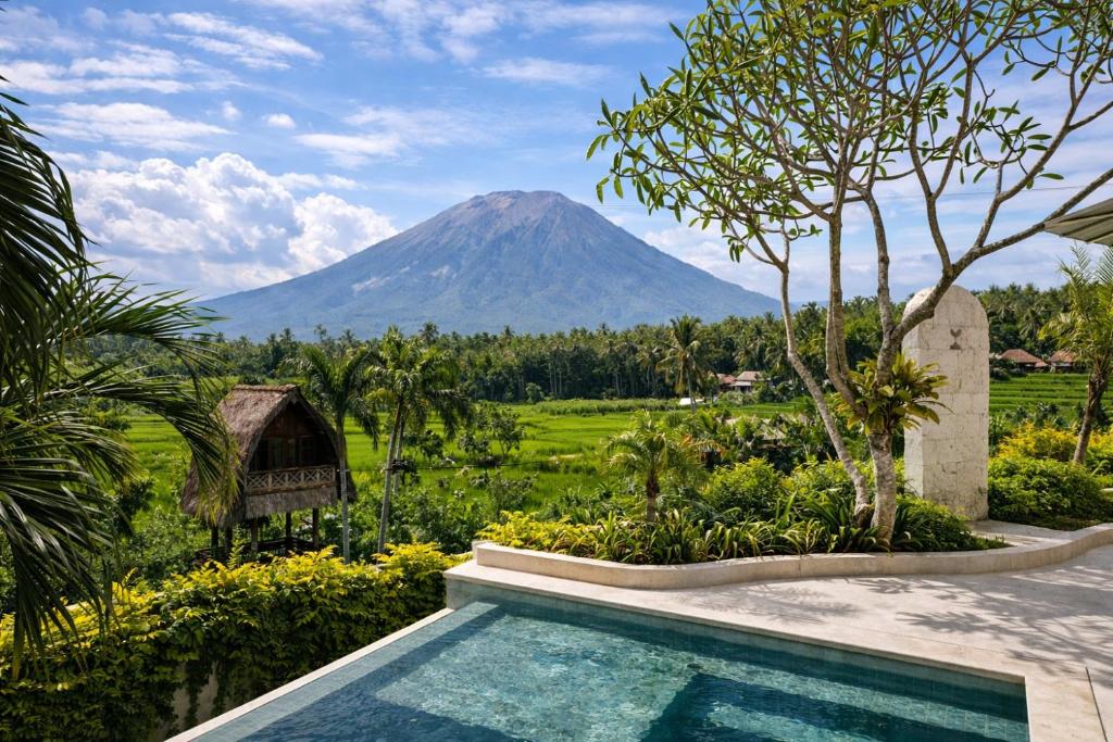 a resort swimming pool with a mountain in the background at Balidroomvilla's in Candidasa