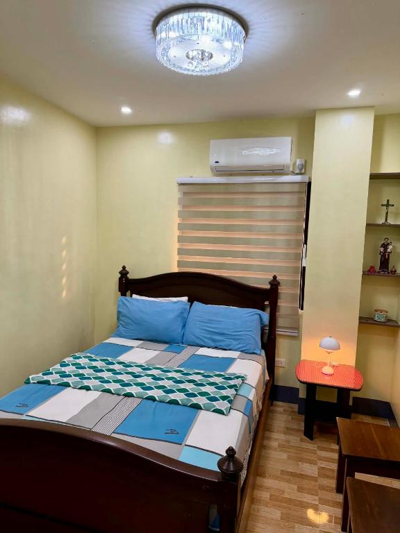 a bedroom with a bed with blue sheets and a chandelier at Henritz Apartelle in Sogod