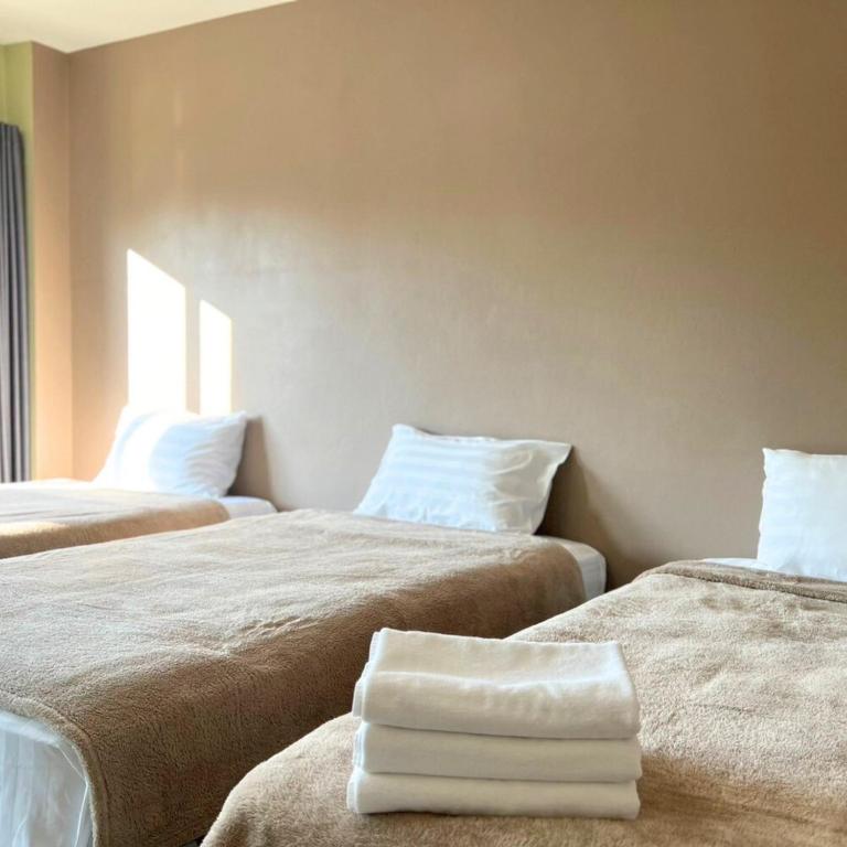 a room with two beds with white towels on them at V Tharm Hotel in Udon Thani