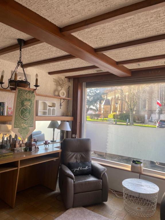 a living room with a chair and a large window at Aux cieux enchanteurs maison magique et spa in Hondschoote