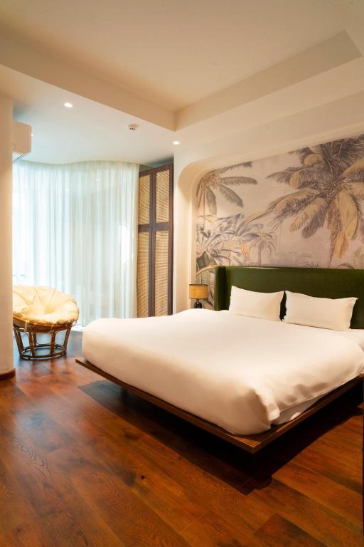 a bedroom with a large white bed with a painting on the wall at Melon Hotel Tố Hữu in Trung Văn