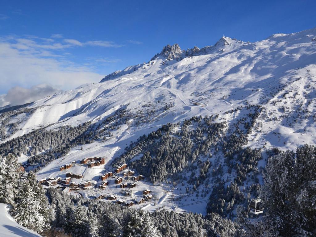 een met sneeuw bedekte berg met een klein stadje erop bij Spacious flat in M ribel near the ski lifts in Méribel