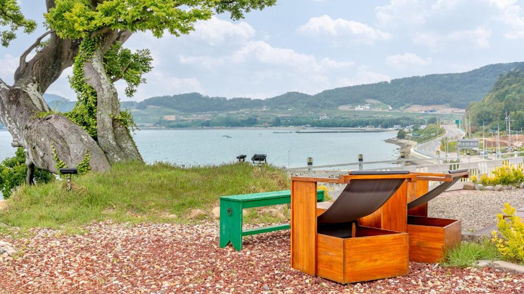a bench sitting on the ground next to a body of water at Yeosu Jangsuri Poolvilla&Spa Pension in Yeosu