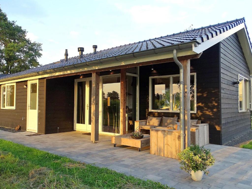 une maison noire avec une véranda dotée de portes en verre dans l'établissement Lovely cottage in the middle of nature, à Keijenborg
