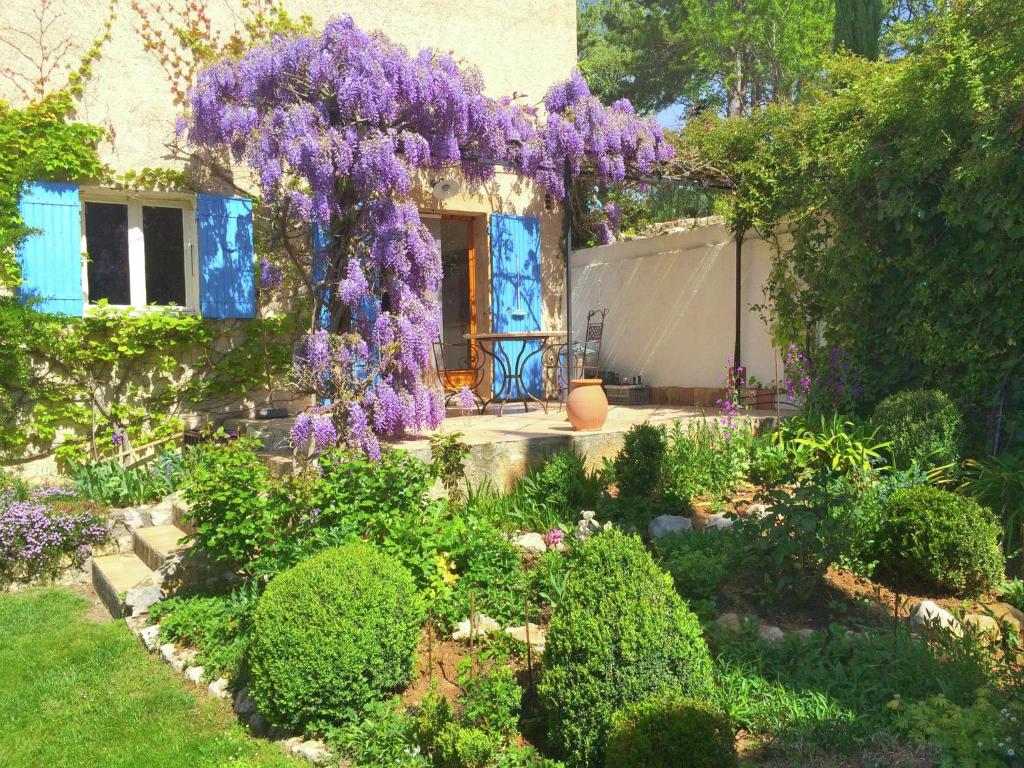 un jardín con glicinas púrpuras colgando de una casa en Lovely g te with private pool, en Montagnac