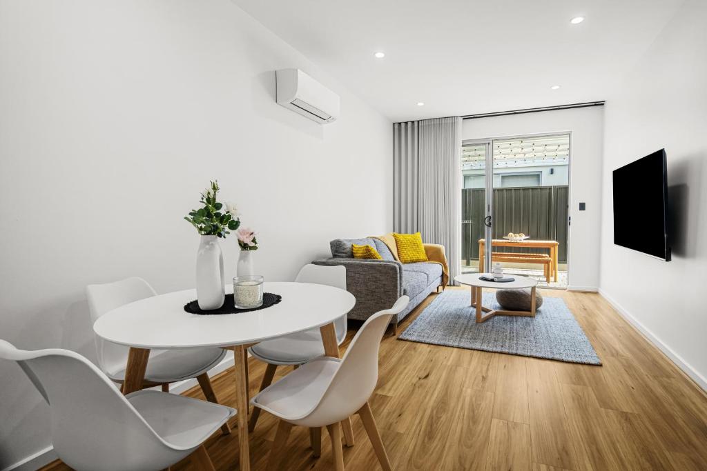 a white living room with a white table and chairs at Chic Flinders Park Getaway in Adelaide