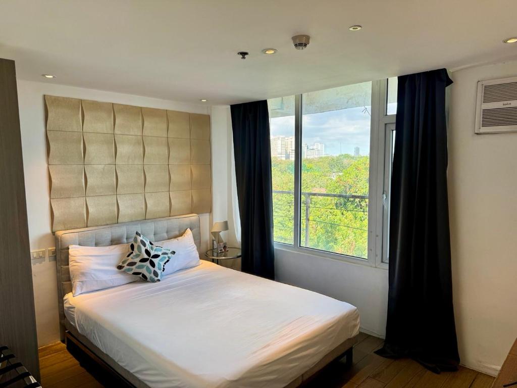 a bedroom with a bed with a large window at City Park Hotel Residences in Manila