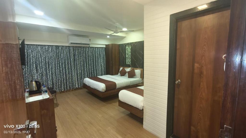 a hotel room with two beds and a door at Hotel Abraj Inn in Mumbai