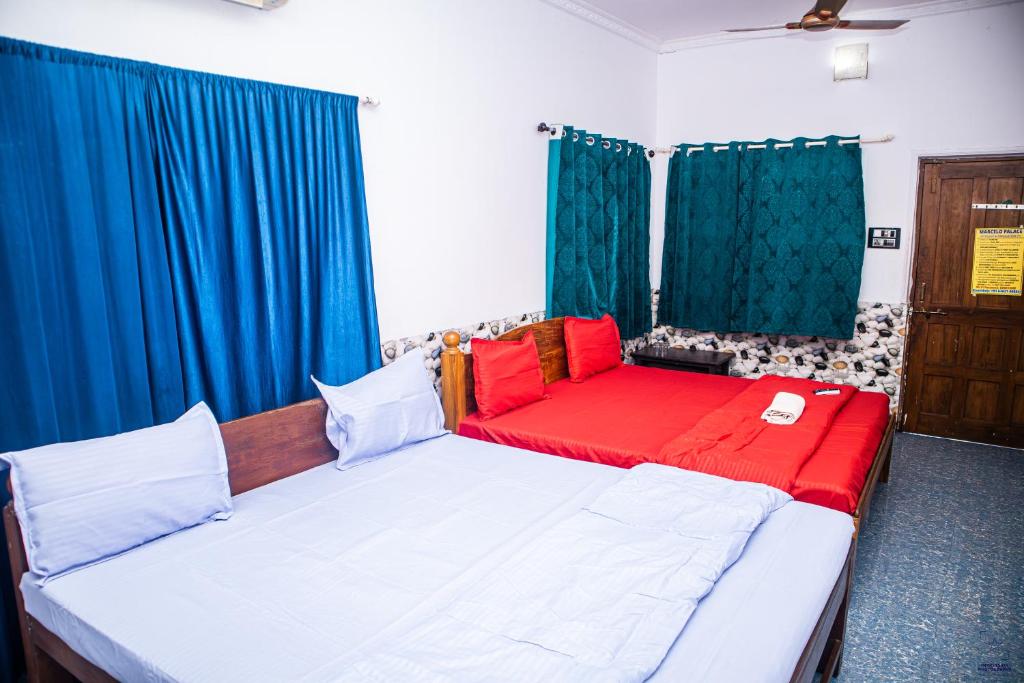 a room with a bed and a couch with blue curtains at Marcelo Palace - Baga in Calangute