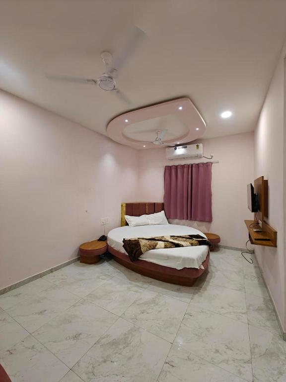 a bedroom with a bed and a tv on the wall at Hotel Avenue Gest House in Dabhoi