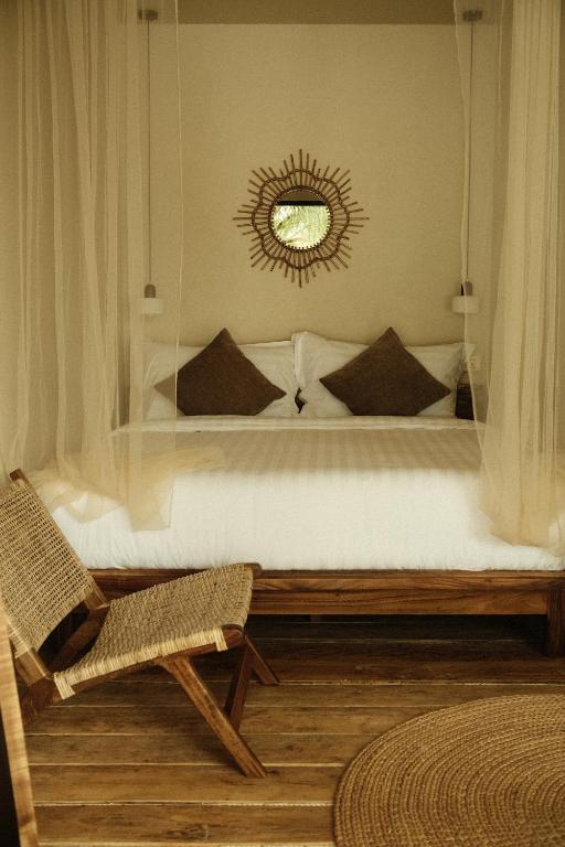 a bedroom with a bed with a mirror and a chair at Sabay Koh Rong in Koh Rong Island