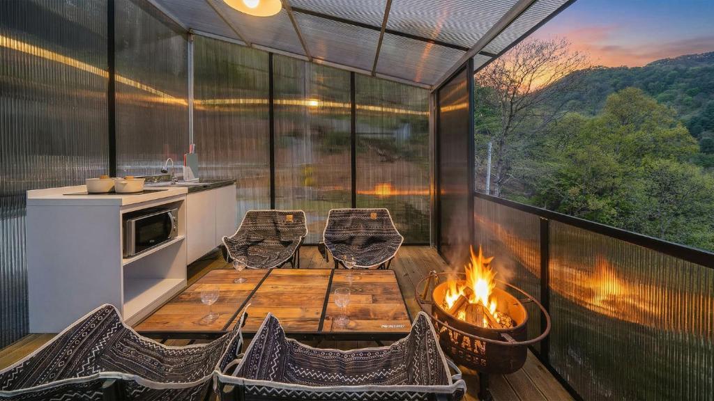 a screened in porch with a table and chairs and a fire pit at Gapyeong Ddobagi Pet & Spa Glamping in Gapyeong