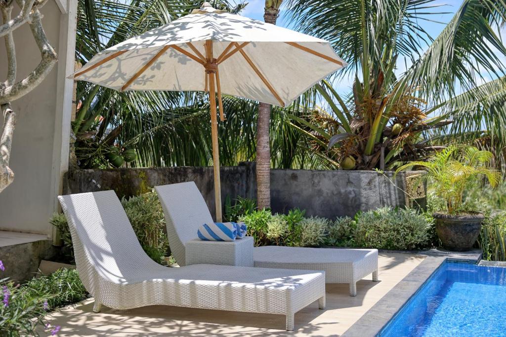 a patio with two chairs and an umbrella next to a pool at Kelingking Point in Nusa Penida