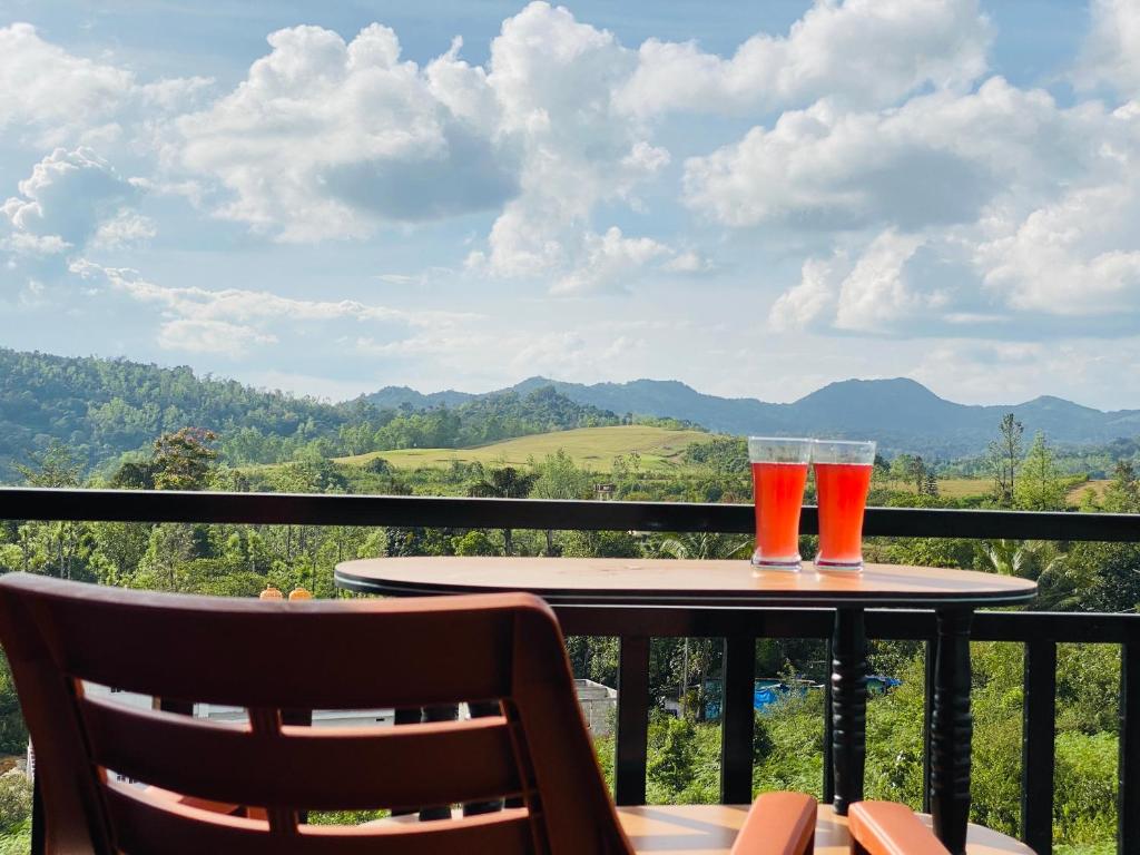 two glasses of beer sitting on a table on a balcony at KODAGU MOUNTAIN VIEW Rooms in Madikeri